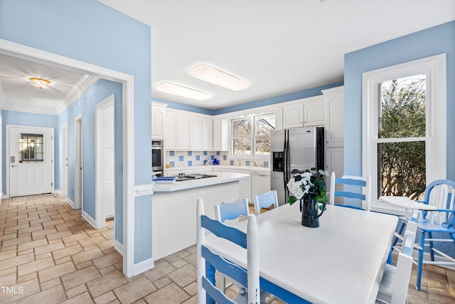 kitchen with tasteful backsplash, crown molding, stainless steel appliances, and white cabinets