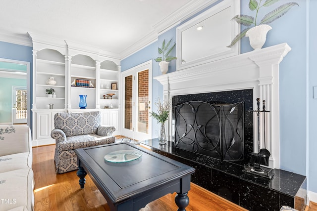 living room featuring hardwood / wood-style floors, crown molding, a high end fireplace, and built in features