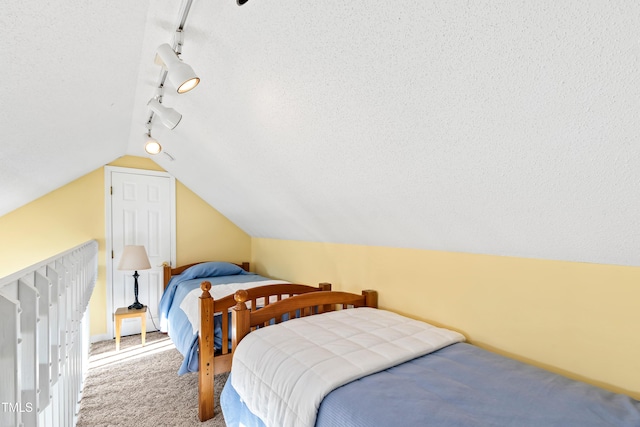 bedroom with lofted ceiling, carpet flooring, and a textured ceiling