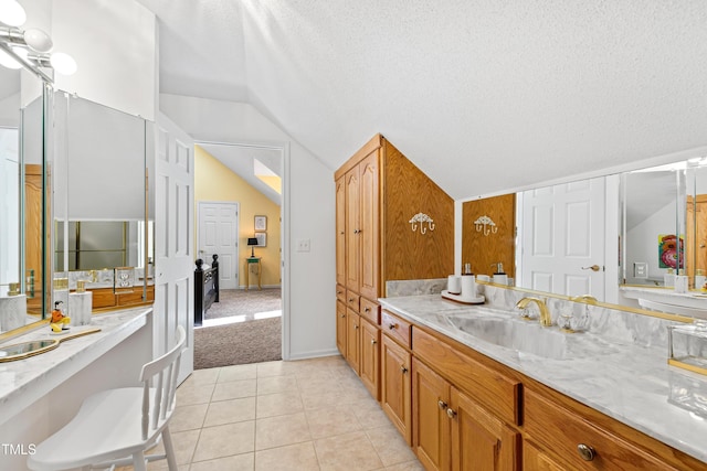 bathroom featuring lofted ceiling, vanity, tile patterned floors, and a textured ceiling
