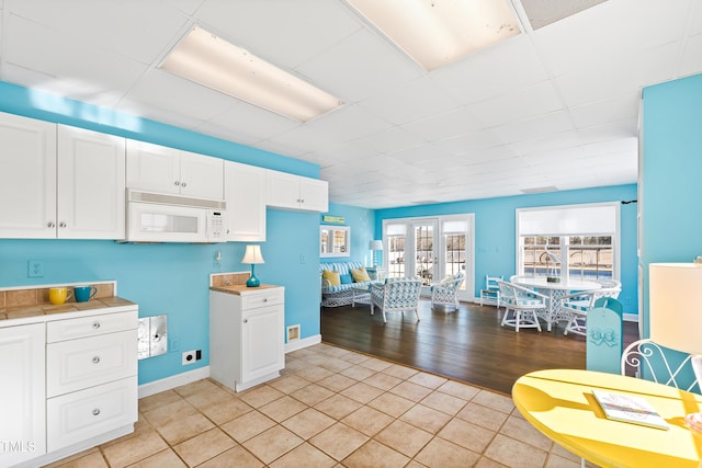 kitchen featuring french doors, light tile patterned flooring, a drop ceiling, and white cabinets