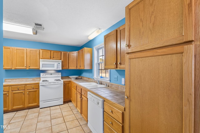 kitchen featuring sink, white appliances, tile countertops, and a textured ceiling