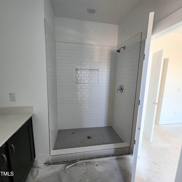 bathroom with tiled shower and vanity