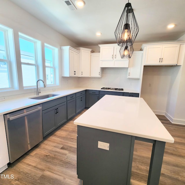 kitchen with sink, a kitchen island, stainless steel appliances, and white cabinetry