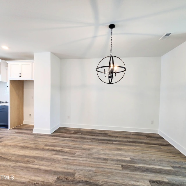 unfurnished dining area featuring dark hardwood / wood-style floors and a chandelier