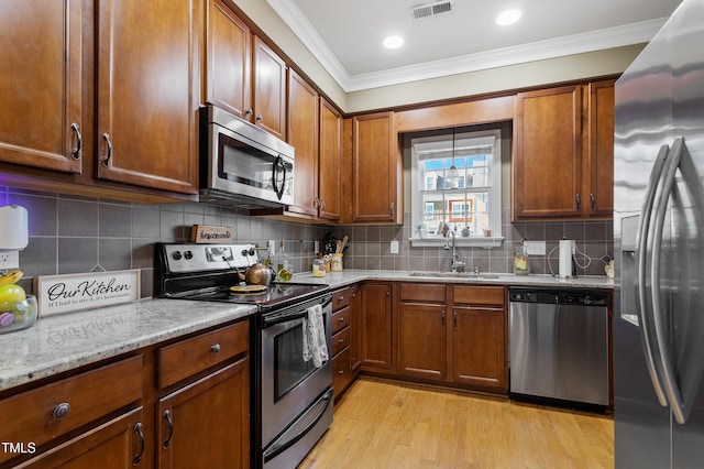 kitchen with sink, backsplash, light hardwood / wood-style flooring, and stainless steel appliances