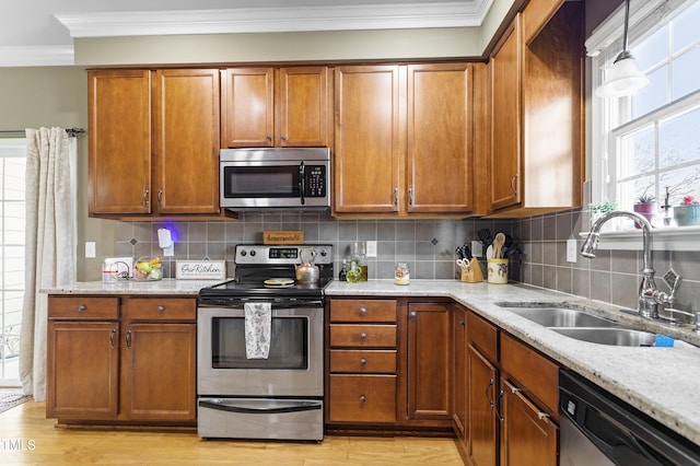 kitchen with sink, light hardwood / wood-style flooring, hanging light fixtures, light stone countertops, and stainless steel appliances