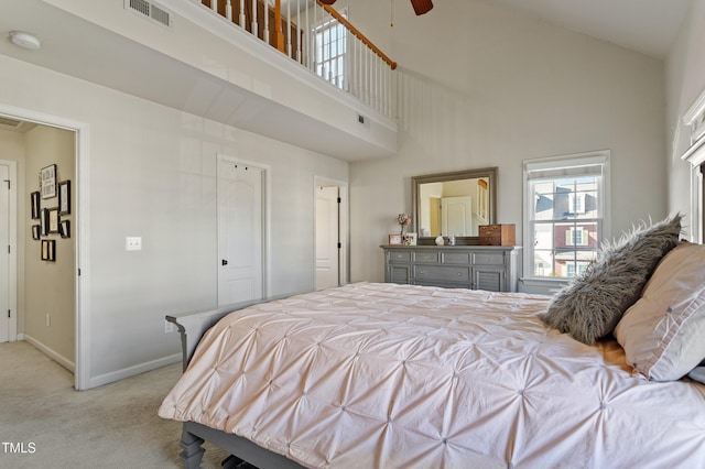 bedroom featuring ceiling fan, light colored carpet, and a high ceiling