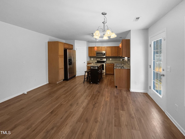 kitchen with a notable chandelier, a kitchen island, pendant lighting, a breakfast bar, and stainless steel appliances