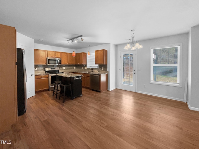 kitchen featuring an inviting chandelier, a breakfast bar area, appliances with stainless steel finishes, hanging light fixtures, and a kitchen island