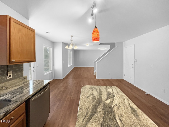 kitchen featuring pendant lighting, dark stone countertops, backsplash, dark hardwood / wood-style floors, and stainless steel dishwasher