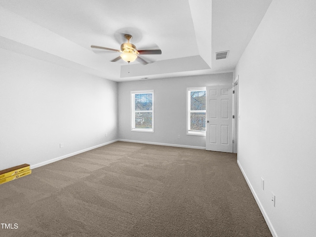 spare room with ceiling fan, carpet floors, and a tray ceiling