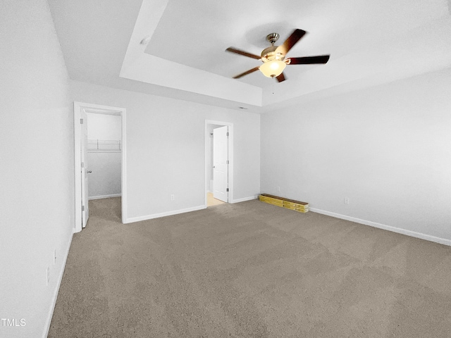 carpeted spare room with ceiling fan and a raised ceiling