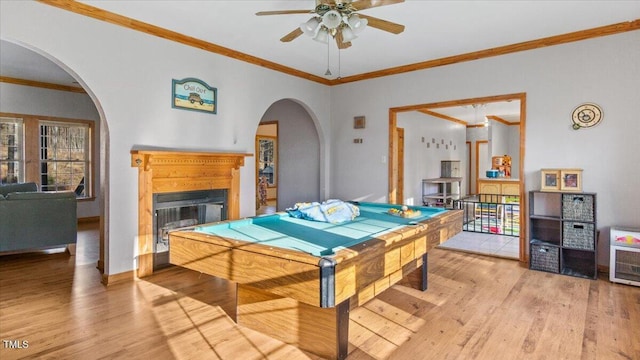 recreation room with ceiling fan, light wood-type flooring, and crown molding