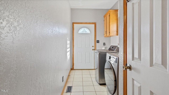 laundry area with cabinets, light tile patterned flooring, and washing machine and clothes dryer