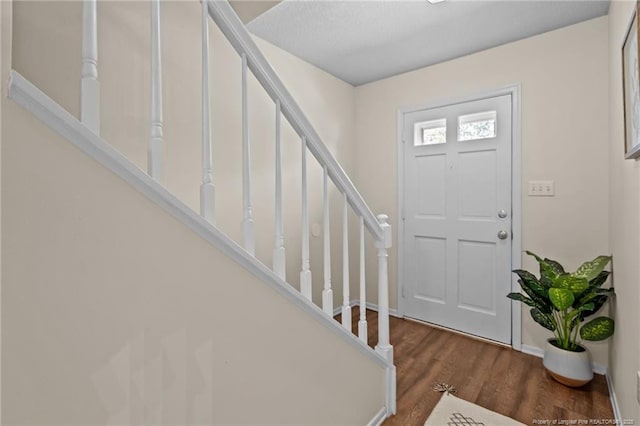 foyer entrance with wood finished floors, baseboards, and stairs