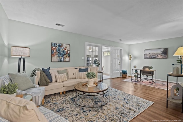 living area featuring visible vents, baseboards, and wood finished floors