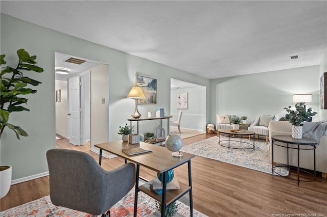 living area featuring visible vents, baseboards, and wood finished floors