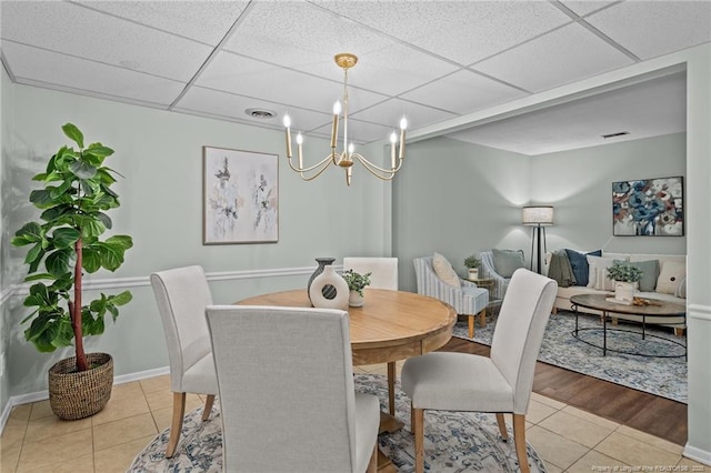 dining area featuring a drop ceiling, baseboards, and tile patterned floors