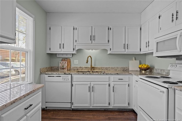 kitchen with white appliances, white cabinets, a sink, and light stone countertops