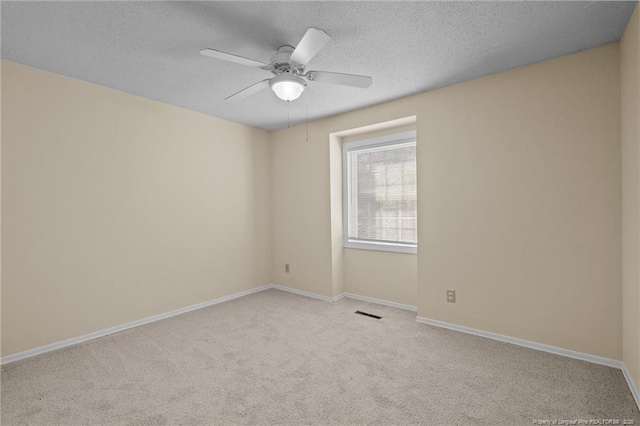 carpeted empty room with visible vents, ceiling fan, a textured ceiling, and baseboards