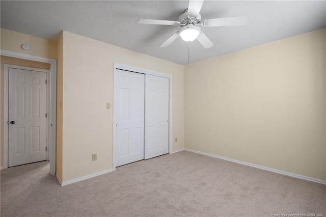 unfurnished bedroom featuring a closet, carpet flooring, a ceiling fan, and baseboards