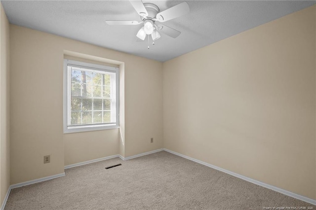 carpeted spare room with ceiling fan, visible vents, and baseboards