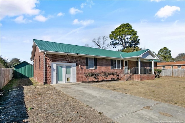 ranch-style house featuring metal roof, brick siding, fence, and covered porch