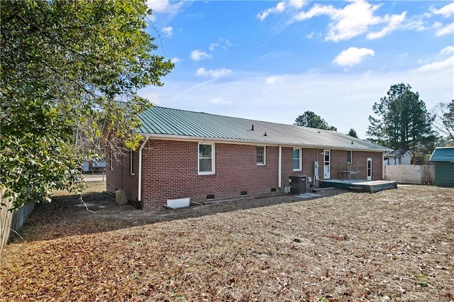 rear view of house featuring metal roof, cooling unit, brick siding, fence, and crawl space