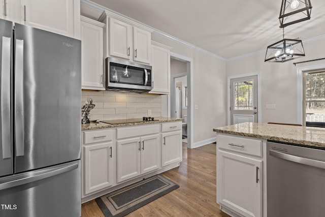 kitchen featuring appliances with stainless steel finishes, white cabinets, decorative backsplash, hanging light fixtures, and crown molding