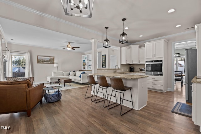 kitchen featuring decorative light fixtures, light stone countertops, white cabinets, and appliances with stainless steel finishes