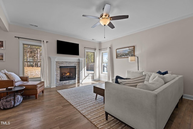 living room featuring ceiling fan, a fireplace, ornamental molding, and dark hardwood / wood-style floors