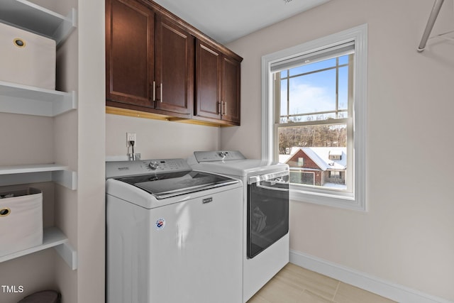 clothes washing area with cabinets, light tile patterned flooring, and washer and clothes dryer