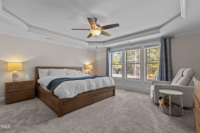 carpeted bedroom featuring ceiling fan, ornamental molding, and a raised ceiling