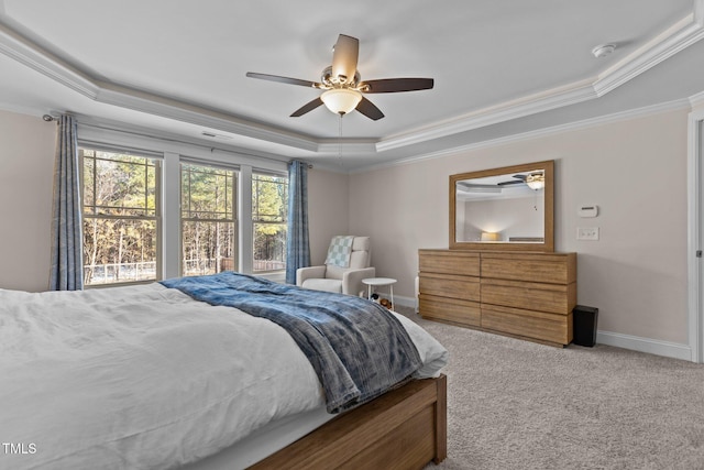 carpeted bedroom with ornamental molding, ceiling fan, and a tray ceiling