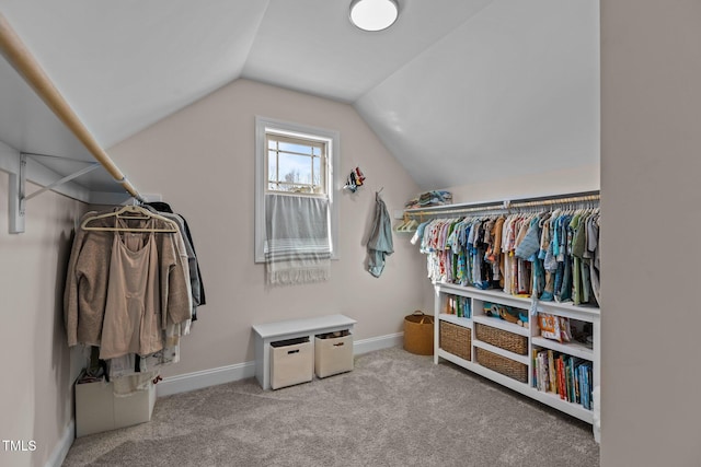 walk in closet with light colored carpet and vaulted ceiling