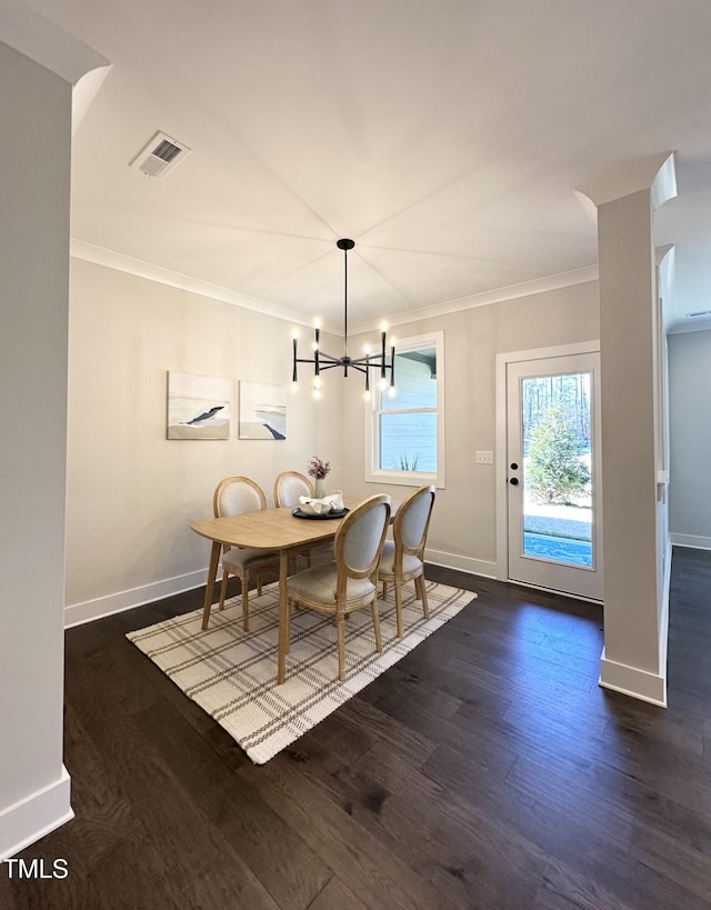 dining space featuring dark hardwood / wood-style flooring, ornamental molding, and a chandelier