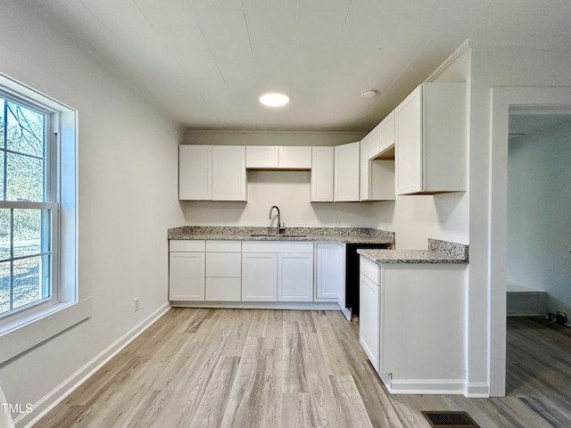 kitchen featuring light stone counters, sink, white cabinetry, and light wood-type flooring