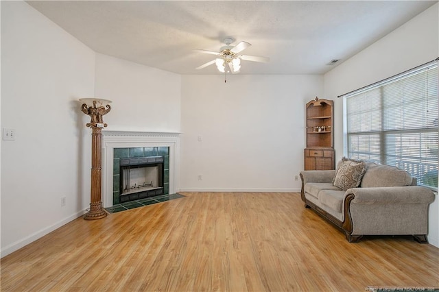 living room with ceiling fan, a tile fireplace, and hardwood / wood-style floors