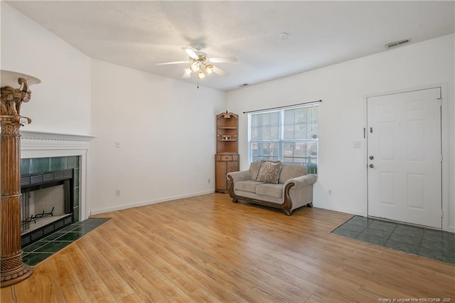 living room featuring ceiling fan, hardwood / wood-style floors, and a tile fireplace