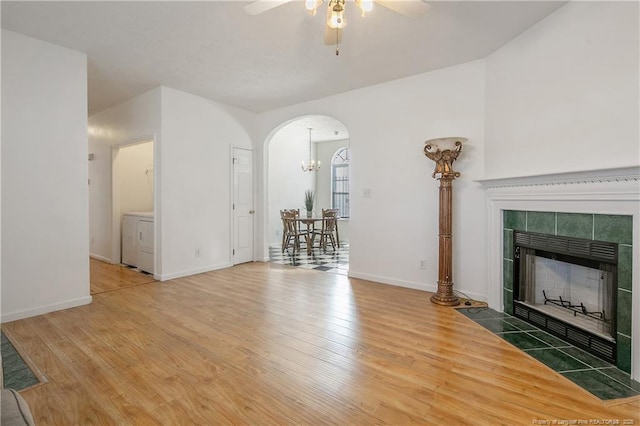 unfurnished living room with ceiling fan, wood-type flooring, and a tiled fireplace