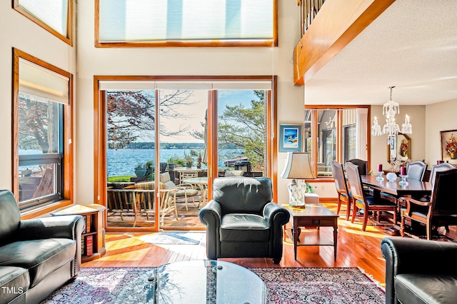 living room with a water view, a textured ceiling, a chandelier, and hardwood / wood-style floors