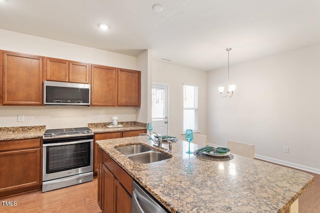 kitchen with stainless steel appliances, sink, hanging light fixtures, a kitchen island with sink, and a chandelier