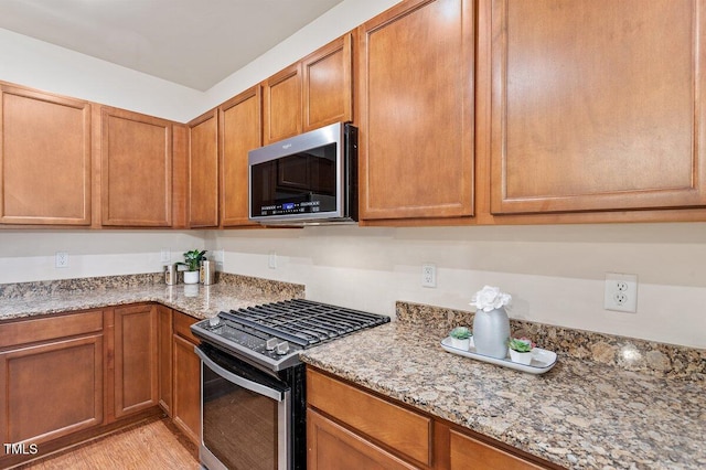 kitchen featuring light stone countertops, stainless steel appliances, and light hardwood / wood-style floors