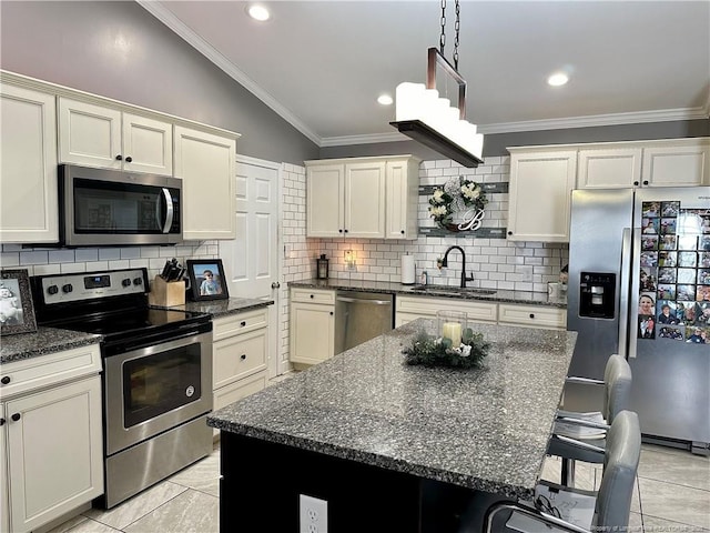 kitchen with vaulted ceiling, appliances with stainless steel finishes, a center island, and sink