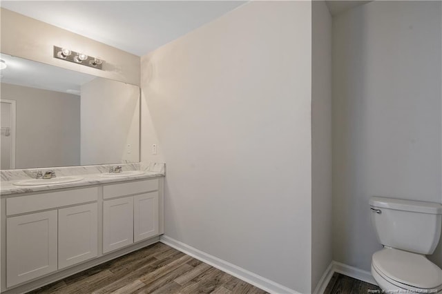 bathroom with toilet, vanity, and wood-type flooring