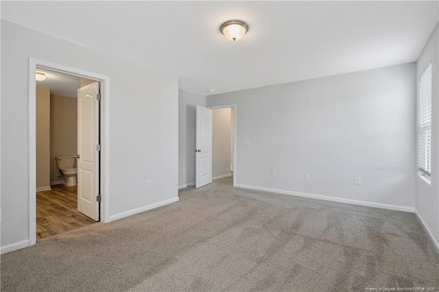 unfurnished bedroom with light colored carpet and connected bathroom