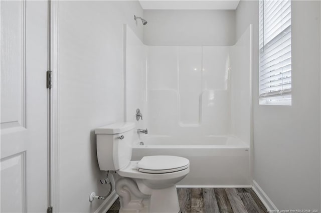 bathroom featuring toilet, washtub / shower combination, and hardwood / wood-style flooring