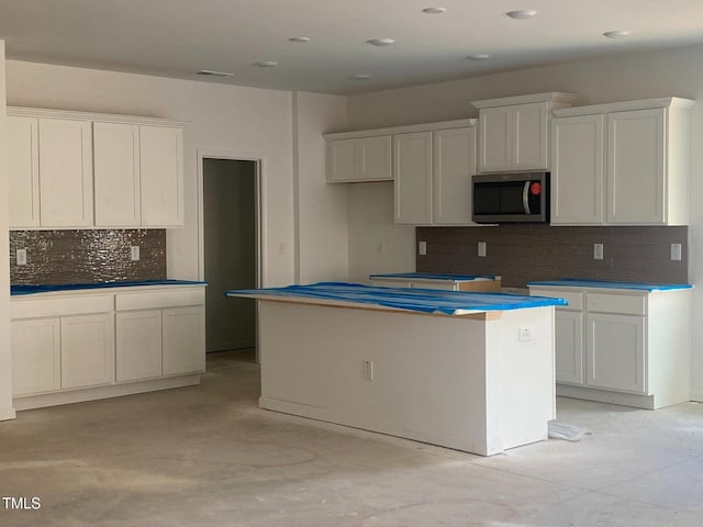 kitchen with tasteful backsplash, white cabinets, and a kitchen island