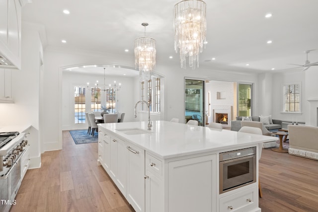 kitchen featuring white cabinetry, pendant lighting, an island with sink, and sink